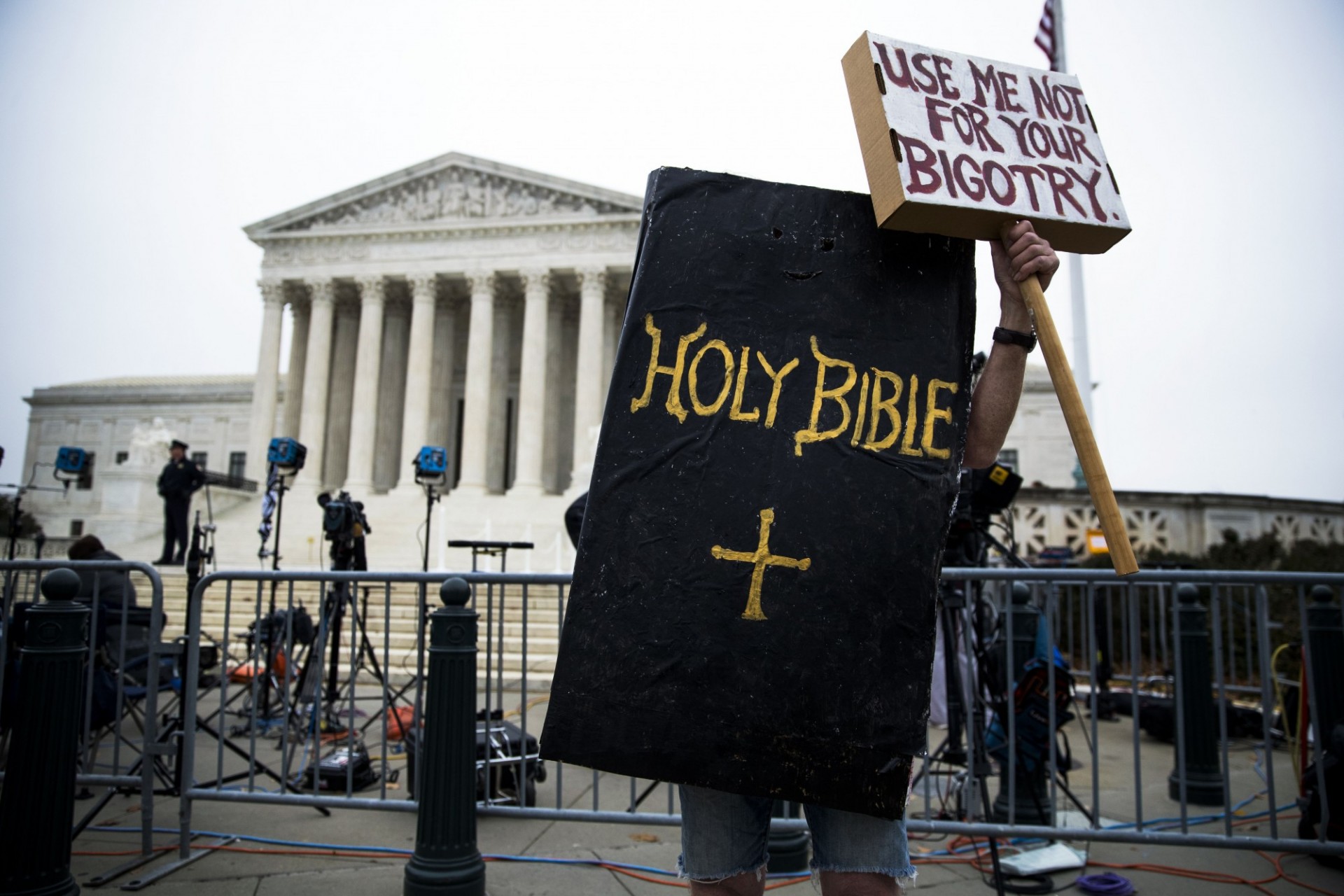 Image of protester outside Supreme Courthouse dressed as a Bible and holding a sign that reads "use me not for your bigotry!"