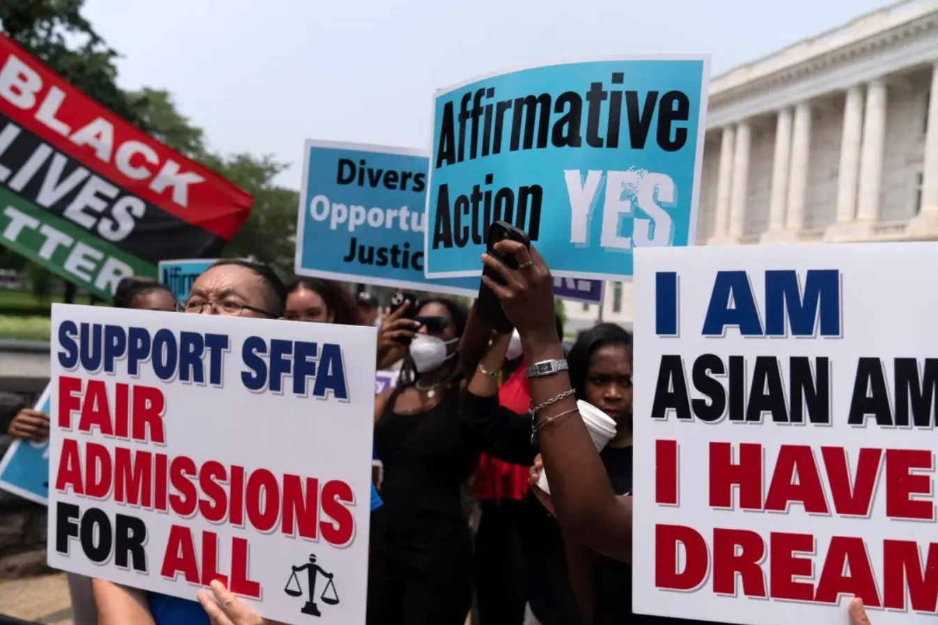 activists hold signs in support of fair admissions for all and affirmative action